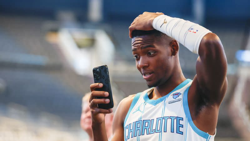 Charlotte Hornets forward Brandon Miller takes a photo with his phone at the NBA basketball’s team media day in Charlotte, N.C., Monday, Oct. 2, 2023.