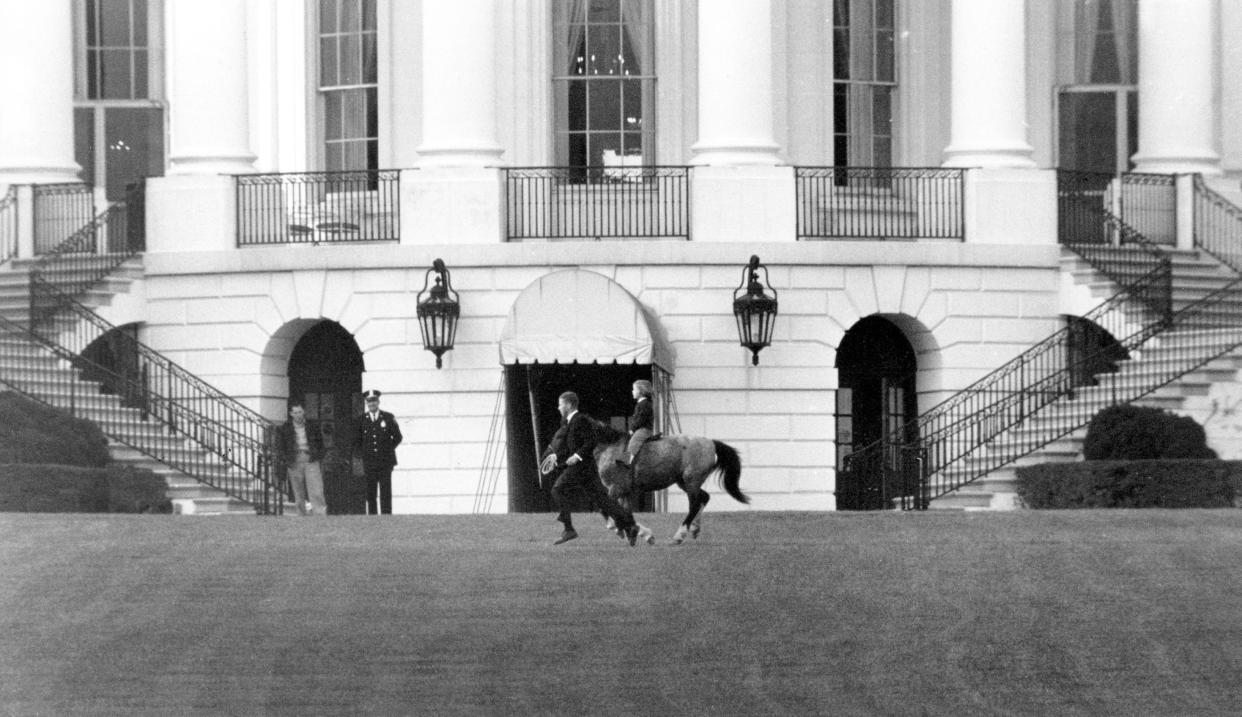 In this March 20, 1962 file photo, President John F. Kennedy's daughter Caroline Kennedy rides her pony, Macaroni, on the south grounds of the White House in Washington. An unidentified handler runs along to keep pace. The arrival of the Biden pets will also mark the next chapter in a long history of pets residing at the White House after a four-year hiatus during the Trump administration. (AP Photo/File)