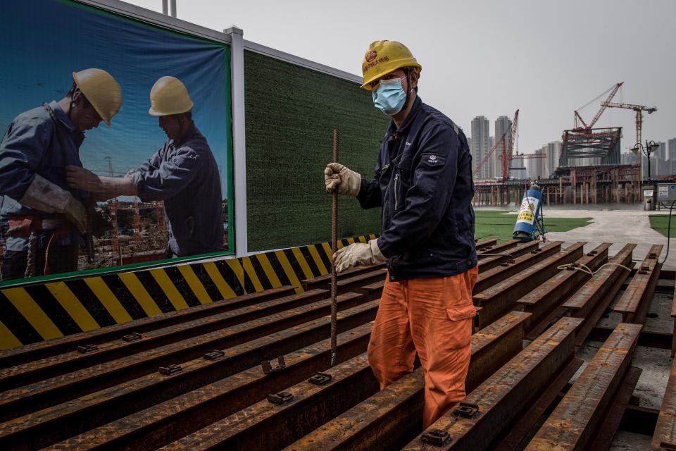 An employee wearing a face mask works at a construction site of a bridge in Wuhan in China's central Hubei province on March 24, 2020. - China announced on March 24 that a lockdown would be lifted on more than 50 million people in central Hubei province where the coronavirus first emerged late last year. (Photo by STR / AFP) / China OUT (Photo by STR/AFP via Getty Images)