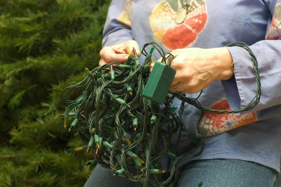 Woman testing a string of Christmas tree lights.