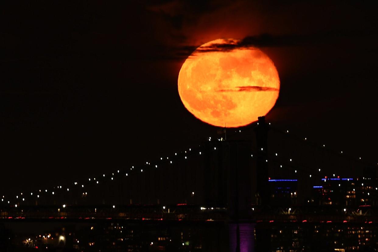 Full moon also known as "Hunter's Moon" rises behind the Brooklyn Bridge in New York City, as seen from Jersey City of New Jersey in United States on October 21, 2021.