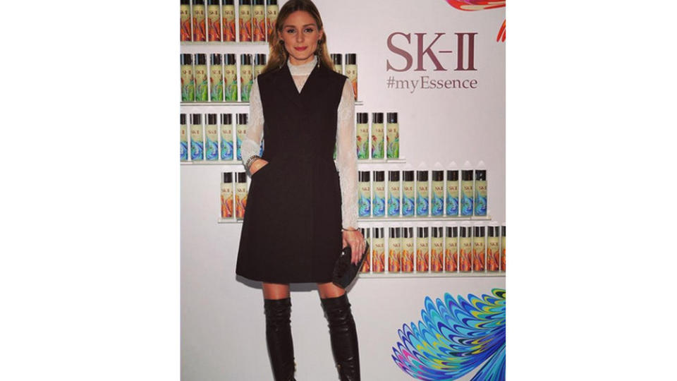 Olivia Palermo kombiniert Overknees zu einem schwarzen Kleid und zeigt ein bisschen Bein