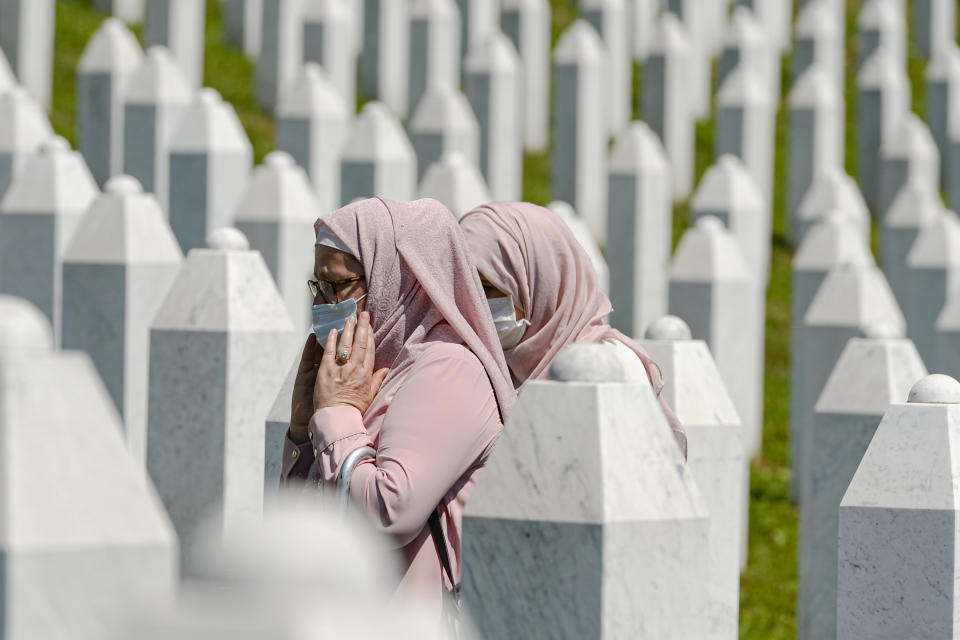 Women walk between grave stones in Potocari, near Srebrenica, Bosnia, Saturday, July 11, 2020. Mourners converged on the eastern Bosnian town of Srebrenica for the 25th anniversary of the country's worst carnage during the 1992-95 war and the only crime in Europe since World War II that has been declared a genocide. (AP Photo/Kemal Softic)