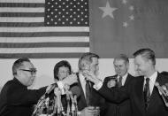 <p>The head of the Iiaison office of the peoples Republic of China Chai Tse-Min, left, and U.S. National Security Affairs Adviser Zbigniew Brzezinski touch glasses the opening of diplomatic relations looks on at center during toasts honoring the opening of diplomatic relations between China and the U.S. in Washington, on Monday, Jan. 2, 1979. At rear, under flags of the U.S. and China, are the wife of the vice-president, Joan Mondale, and Secretary of State Cyrus Vance. (Photo: Ira Schwarz/AP) </p>