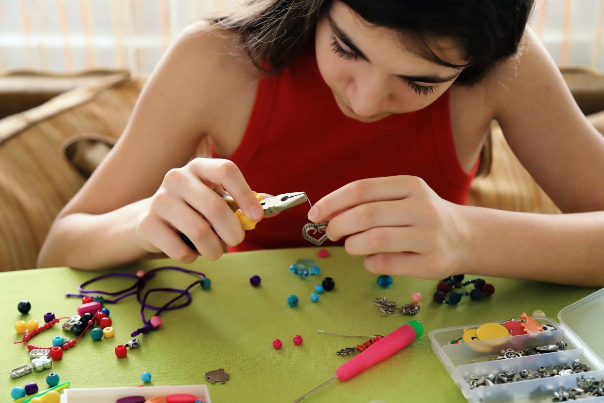 Young girl making bead bracelets at home