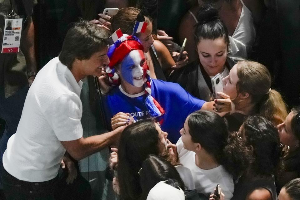 El actor Tom Cruise, izquierda, se toma fotos con fans mientras asiste a la ronda de clasificación de gimnasia artística femenina en los Juegos Olímpicos de Verano de 2024, el domingo 28 de julio de 2024, en París, Francia. (Foto AP/Morry Gash)
