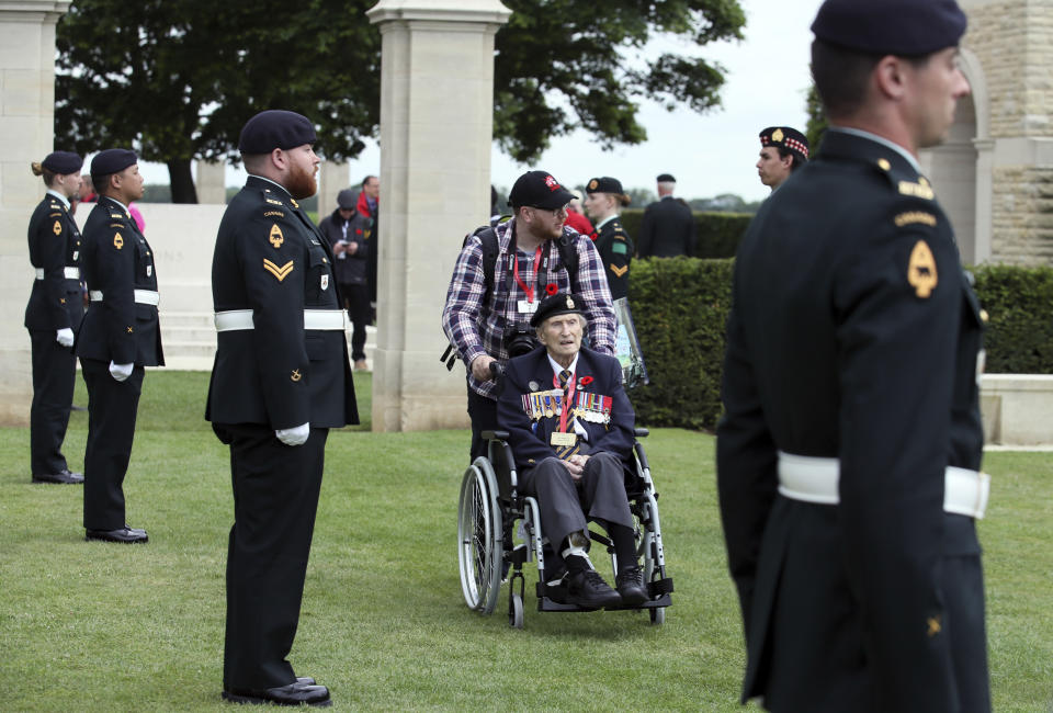Canadian World War II veteran Jim Warford, center, arrives for a ceremony at the Beny-sur-Mer Canadian War Cemetery in Reviers, Normandy, France, Wednesday, June 5, 2019. The cemetery contains 2,049 headstones marking the dead of the 3rd Division and graves of 15 airmen. (AP Photo/David Vincent)