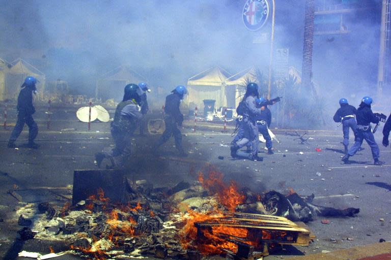 Police pass by burning debris following clashes with anti-globalisation protesters against the G8 summit in Genoa, Italy, on July 21, 2001