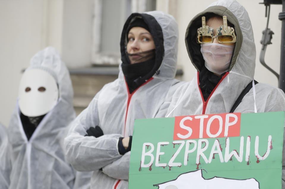 FILE - In this Saturday, Dec. 19, 2020 file photo, participants with a sign reading "Stop Lawlessness" and wearing anti-COVID-19 overalls take part in a protest against new pandemic restrictions and planned lockdown during the holiday season before the Health Ministry in Warsaw, Poland. The coronavirus pandemic has upended life around the globe, but it has hasn’t stopped the spread of authoritarianism and extremism. Some researchers believe it may even have accelerated it, but curbing individual freedoms and boosting the reach of the state. Since COVID-19 hit, Hungary has banned children from being told about homosexuality. China shut Hong Kong’s last pro-democracy newspaper. Brazil’s president has extolled dictatorship. Belarus has hijacked a passenger plane. A Cambodian human rights lawyer calls the pandemic “a dictator's dream opportunity.” But there are also resistance movements, as protesters from Hungary to Brazil take to the streets to defend democracy. (AP Photo/Czarek Sokolowski, File)