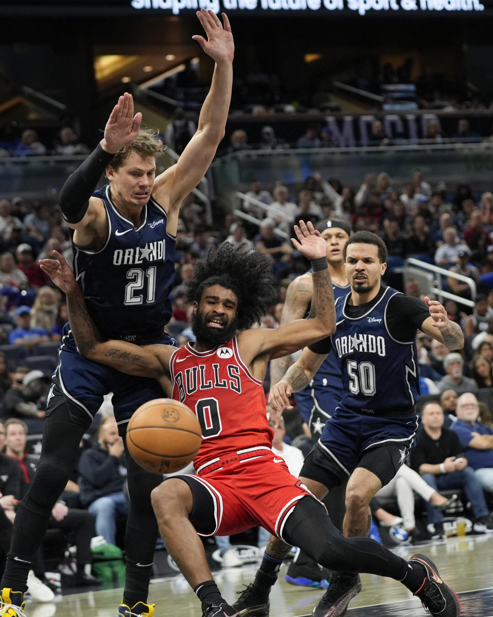 Chicago Bulls guard Coby White (0) falls as he is fouled by Orlando Magic center Moritz Wagner (21) after getting past Orlando Magic guard Cole Anthony (50) during the second half of an NBA basketball game, Sunday, April 7, 2024, in Orlando, Fla. (AP Photo/John Raoux)