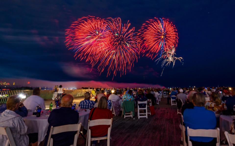 People watch the Milwaukee lakefront fireworks display from the patio of the Milwaukee War Memorial Center on Sunday, July 3, 2022 in Milwaukee, Wis.