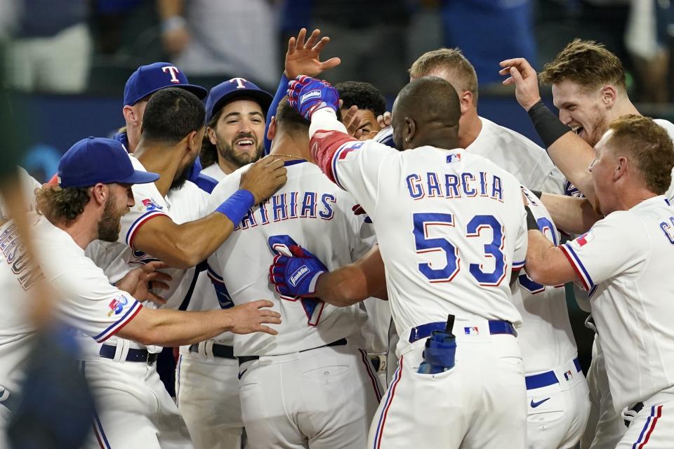 Texas Rangers' Mark Mathias, center, is welcomed at home plate by teammates after hitting a game-ending home run in the team's 8-7 win in a baseball game against the Oakland Athletics in Arlington, Texas, Tuesday, Sept. 13, 2022. (AP Photo/Tony Gutierrez)