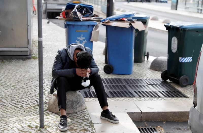 A man holds a protective mask in his hands as he rests at Restauradores Square in downtown Lisbon