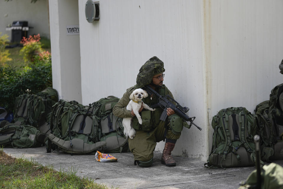 An Israeli soldier holds a dog in kibbutz Kfar Azza on Tuesday. (Ohad Zwigenberg/AP)