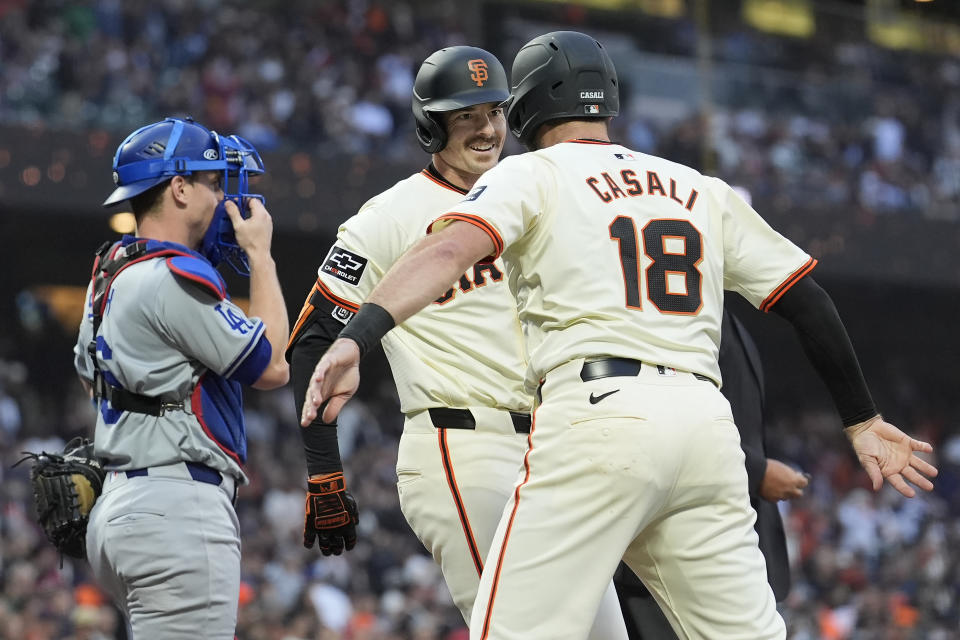 San Francisco Giants' Mike Yastrzemski, middle, celebrates after hitting a two-run home run that also scored Curt Casali (18), next to Los Angeles Dodgers catcher Will Smith, left, during the third inning of a baseball game in San Francisco, Wednesday, May 15, 2024. (AP Photo/Jeff Chiu)