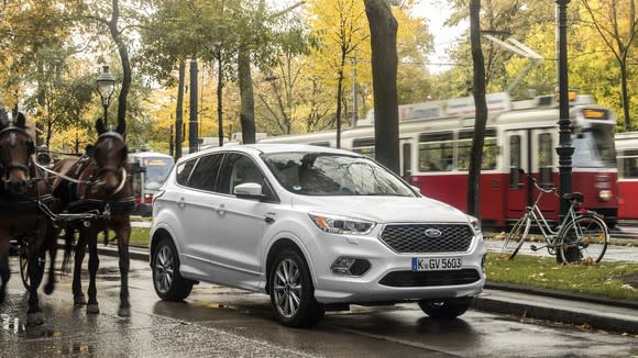 A white Ford Kuga, a compact SUV, on a city street.