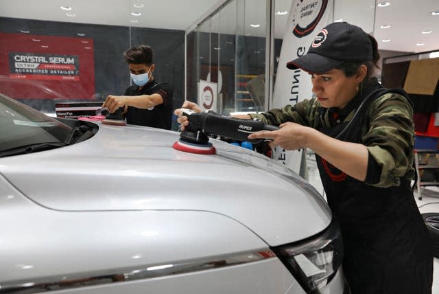 Maryam Roohani, right, and her brother Reza polish a car at a detailing shop in Tehran, Iran 