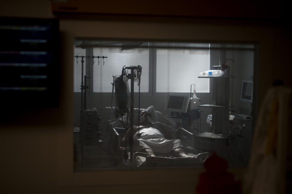 A 60-year-old COVID-19 patient is pictured through the window of an ICU room at the La Timone hospital in Marseille, southern France, Thursday, Nov. 12, 2020. (AP Photo/Daniel Cole)