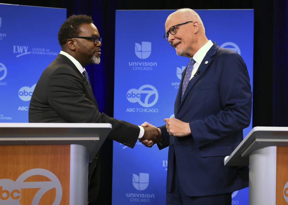 Mayoral candidates Brandon Johnson and Paul Vallas shake hands.