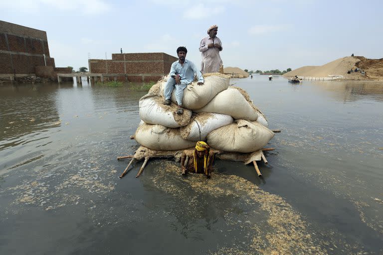 Víctimas de inundaciones provocadas por las lluvias monzónicas usan una balsa improvisada con el fin de transportar paja para el ganado, el 5 de septiembre de 2022, en Jaffarabad, un distrito de la provincia de Baluchistán, en el suroeste de Pakistán.