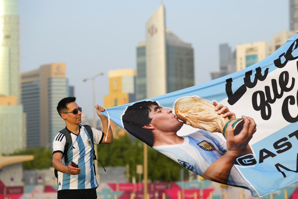 Argentinian fan holds up banner with soccer legend Diego Maradona as the fan zone opens ahead of the FIFA World Cup in Doha, Qatar, Saturday, Nov. 19, 2022. (AP Photo/Petr David Josek)