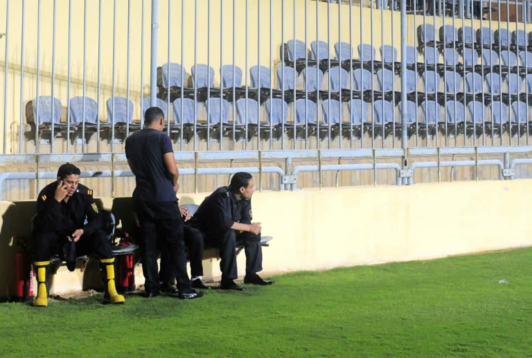 Members of the Egyptian security forces sit in front of empty stands during a league football match in Cairo on July 15, 2015