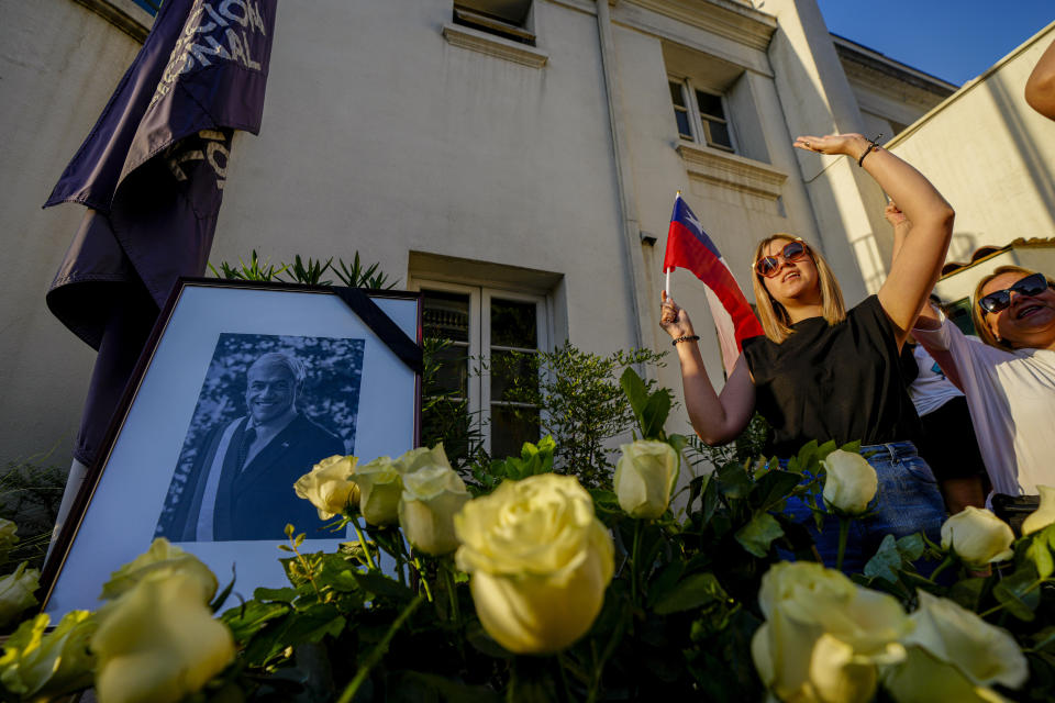 Simpatizantes cantan el himno nacional y gritan "larga vida a Piñera", junto al retrato del fallecido expresidente chileno Sebastián Piñera en el punto de homenaje colocado en la sede del partido Renovación Nacional, en Santiago, Chile, el martes 6 de febrero de 2024. El dos veces presidente chileno murió el martes en un accidente de helicóptero a los 74 años. (AP Foto/Esteban Félix)