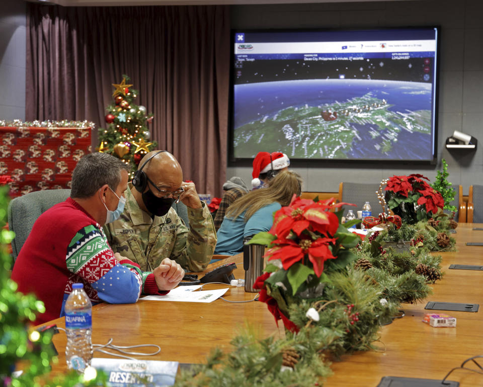 This image provided by the Department of Defense shows volunteers answering phones and emails from children around the globe during the annual NORAD Tracks Santa event on Peterson Air Force Base in Colorado Springs, Colo., Dec. 24, 2021. (Chuck Marsh/Department of Defense via AP)