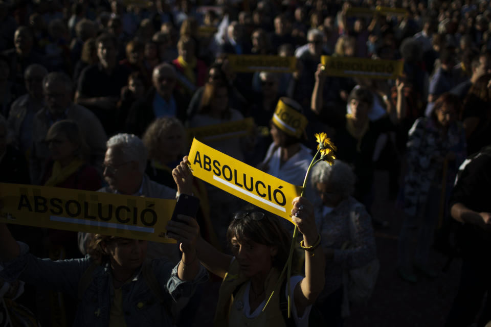 An independence demonstrator holds a banner reading in Catalan "absolution" during a protest in downtown Barcelona, Spain, Wednesday, June 12, 2019. Catalan separatist leaders and activists told their Supreme Court trial on Wednesday they were exercising their democratic rights when they held a banned referendum on breaking away from Spain, denying charges of rebellion and sedition. (AP Photo/Emilio Morenatti)