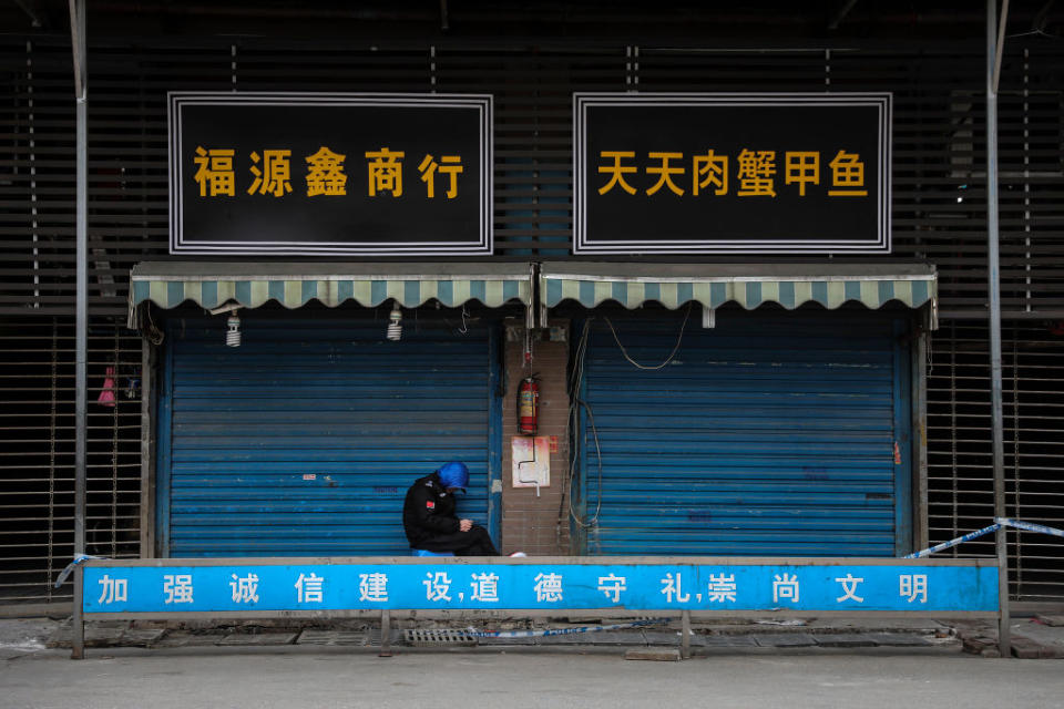 A security guard sits outside the closed Huanan Seafood Wholesale Market, which has been linked to cases of Coronavirus.