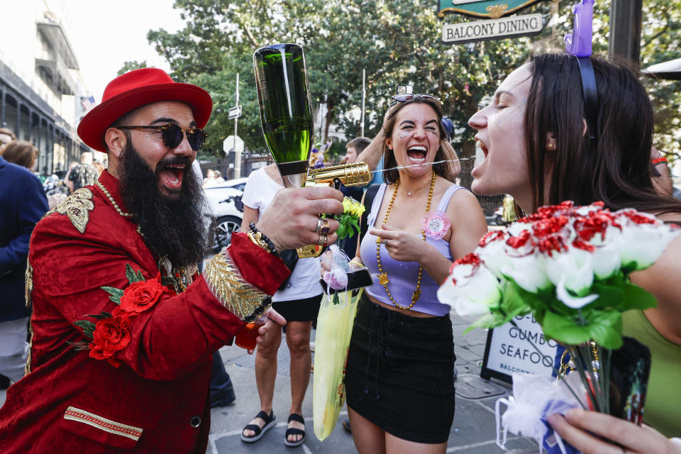 A person sprays champagne into the mouth of another Mardi Gras reveler in the French Quarter in New Orleans, Friday, Feb. 9, 2024. (Sophia Germer/The Times-Picayune/The New Orleans Advocate via AP)