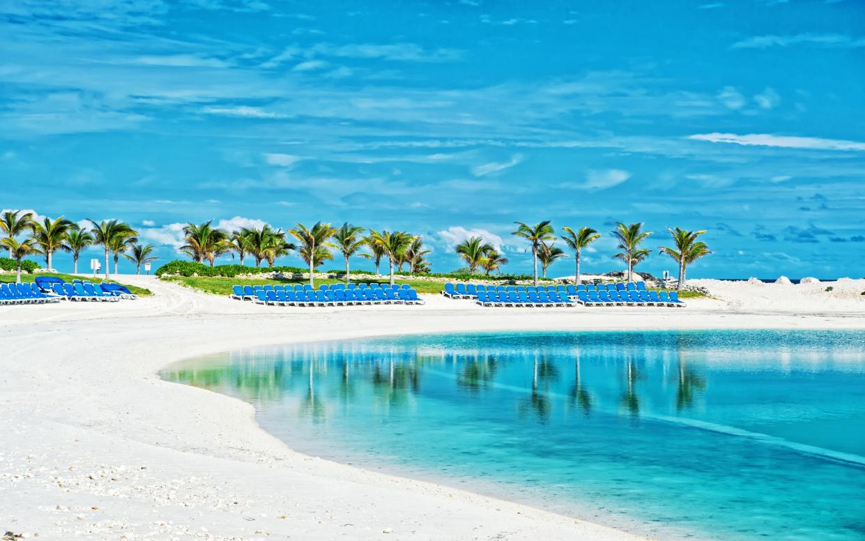 Tropical beach in Great Stirrup Cay, Bahamas. Sea shore, white sand, palm trees on blue sky.