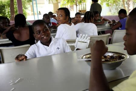 Handicapped Haitian boy Stevenson Joseph (C), wears the 3D-printed prosthetic hand that he is learning to use while having a meal at the orphanage where he lives in Santo, near Port-au-Prince, April 28, 2014. REUTERS/Marie Arago