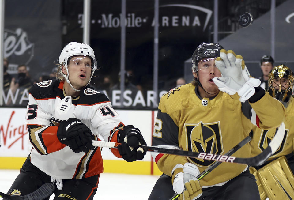 Vegas Golden Knights defenseman Zach Whitecloud (2) grabs an airborne puck next to Anaheim Ducks left wing Danton Heinen (43) during the first period of an NHL hockey game Saturday, Jan. 16, 2021, in Las Vegas. (AP Photo/Isaac Brekken)