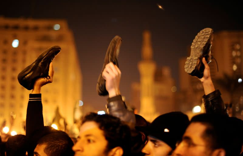 FILE PHOTO: Anti-government protesters in Cairo's Tahrir Square wave shoes in dismay as President Hosni Mubarak speaks to the nation
