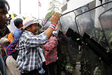 A farmer gestures in front of soldiers guarding the temporary office of Thai Prime Minister Yingluck Shinawatra during a protest in Bangkok February 17, 2014. REUTERS/Chaiwat Subprasom