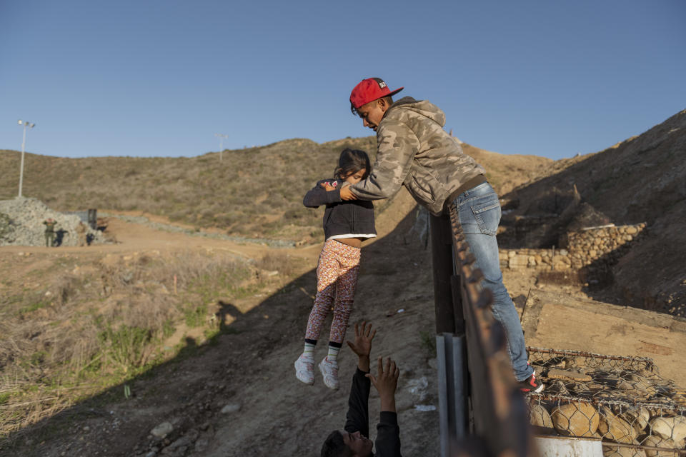 A migrant from Honduras pass a child to her father after he jumped the border fence to get into the U.S. side to San Diego, Calif., from Tijuana, Mexico, Thursday, Jan. 3, 2019. Discouraged by the long wait to apply for asylum through official ports of entry, many migrants from recent caravans are choosing to cross the U.S. border wall and hand themselves in to border patrol agents. (AP Photo/Daniel Ochoa de Olza)