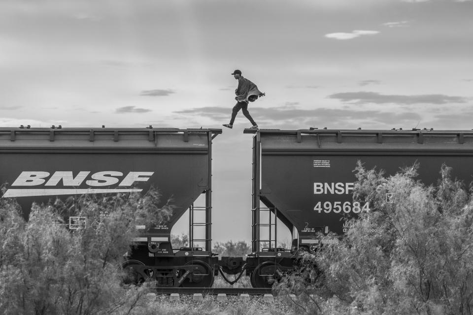 This image provided by World Press Photo and taken by Alejandro Cegarra for The New Times/Bloomberg is part of a series titled The Two Walls which won the World Press Photo Long-Term Project Award and shows a migrant walking atop a freight train known as "The Beast." Migrants and asylum seekers lacking the financial resources to pay a smuggler often resort to using cargo trains to reach the United States border. This mode of transportation is very dangerous; over the years, hundreds have fallen onto the tracks and have been killed or maimed. Piedras Negras, Mexico, 8 October 2023. (Alejandro Cegarra/The New York Times/Bloomberg/World Press Photo via AP)