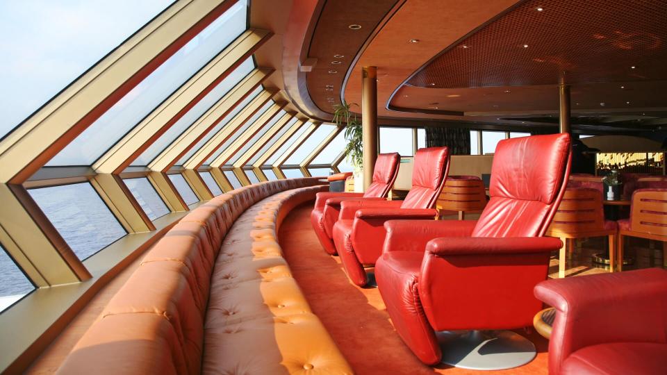 Row of leather armchairs facing windows overlooking the sea.