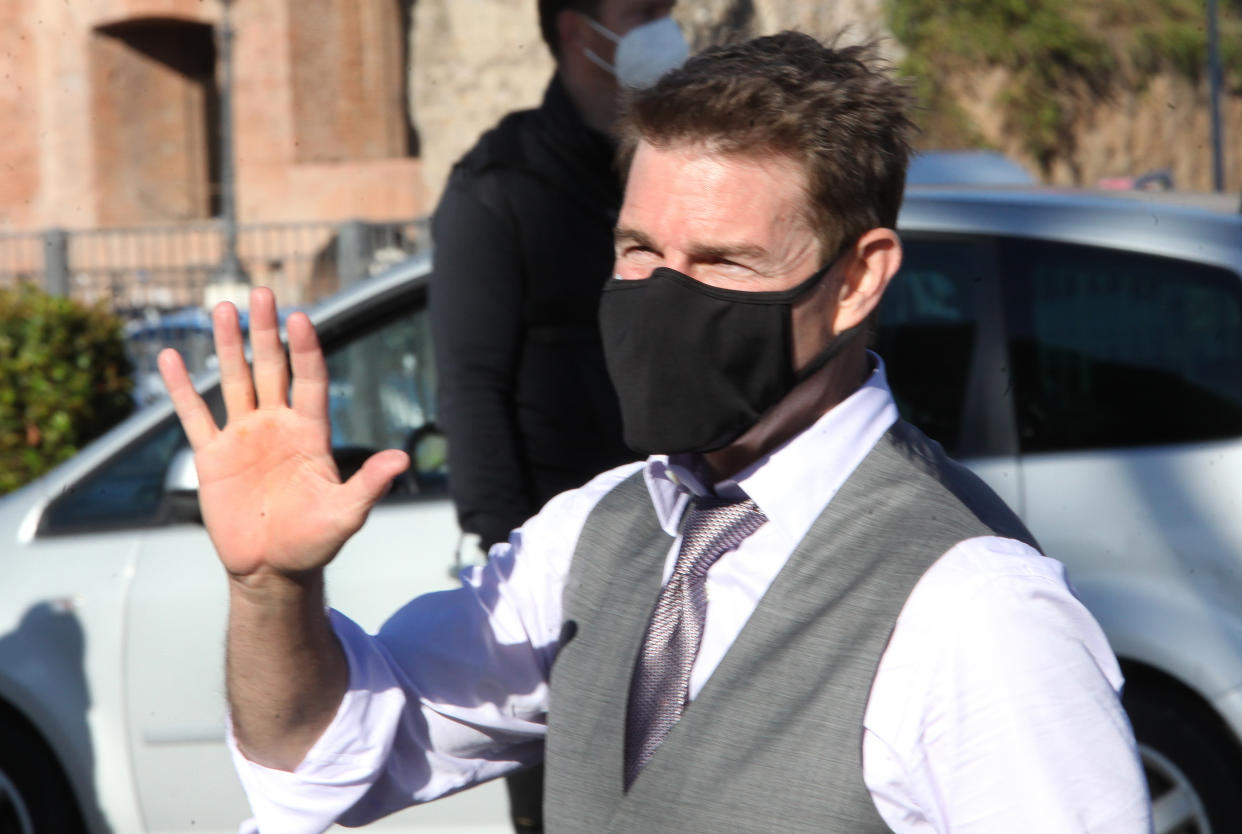 Tom Cruise wears a face mask to prevent the spread of COVID-19 as he waves to fans during a break from shooting the film Mission Impossible 7- Libra, along Rome's Fori Imperiali avenue 