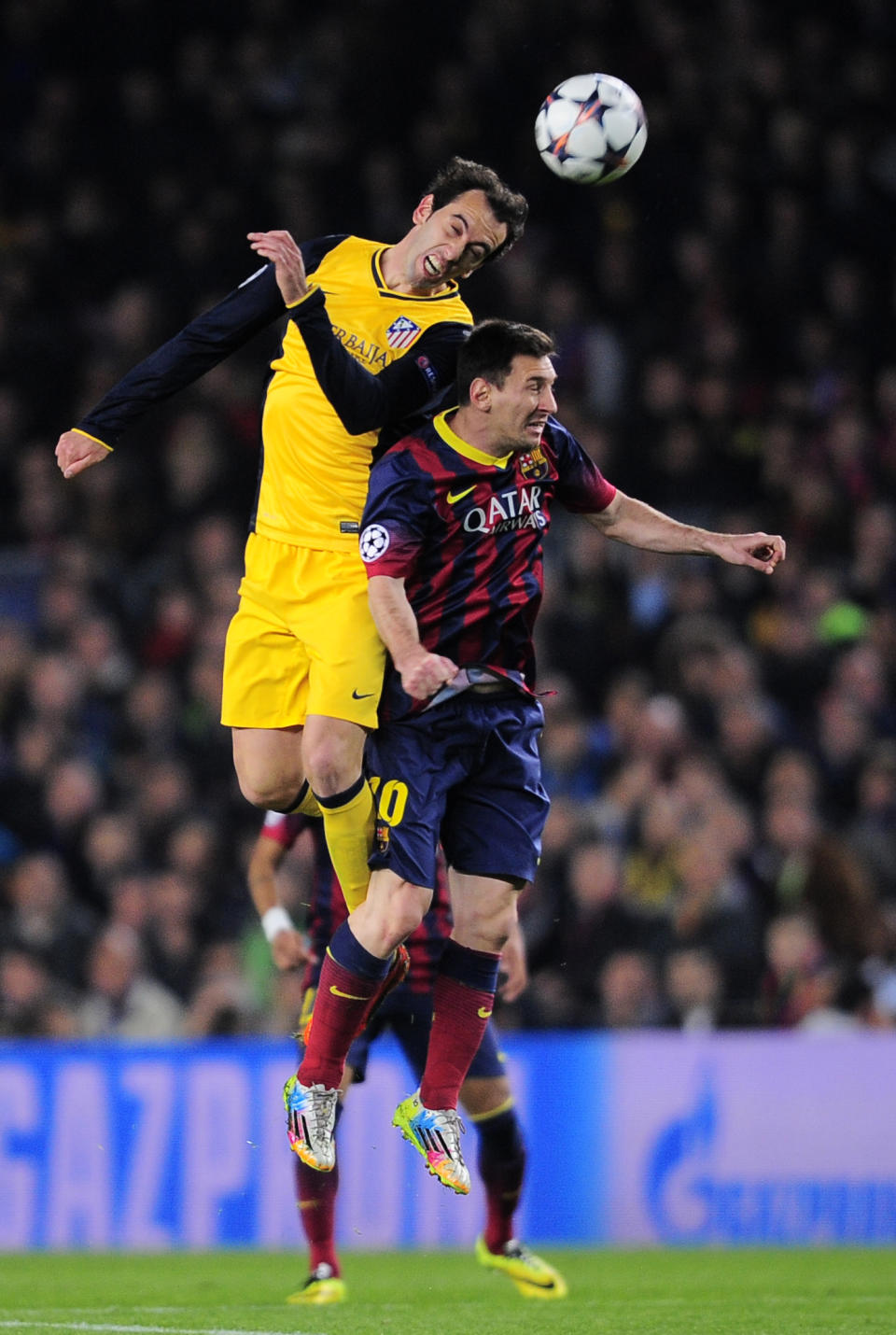 Atletico's Diego Godin, left out jumps Barcelona's Lionel Messi during a first leg quarterfinal Champions League soccer match between Barcelona and Atletico Madrid at the Camp Nou stadium in Barcelona, Spain, Tuesday April 1, 2014. (AP Photo/Manu Fernandez)