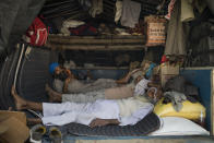 Farmers rest in the back of their tractor trailer as they block a major highway during a protest to abolish new farming laws they say will result in exploitation by corporations, eventually rendering them landless, at the Delhi-Haryana state border, India, Tuesday, Dec. 1, 2020. The busy, nonstop, arterial highways that connect most northern Indian towns to this city of 29 million people, now beat to the rhythm of never-heard-before cries of "Inquilab Zindabad" ("Long live the revolution"). Tens and thousands of farmers, with colorful distinctive turbans and long, flowing beards, have descended upon its borders where they commandeer wide swathes of roads. (AP Photo/Altaf Qadri)