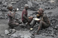 In this Oct. 23, 2019, photo, laborers eat lunch at a coal loading site in the village of Godhar in Jharia, a remote corner of eastern Jharkhand state, India. The fires started in coal pits in eastern India in 1916. More than a century later, they are still spewing flames and clouds of poisonous fumes into the air, forcing residents to brave sizzling temperatures, deadly sinkholes and toxic gases. (AP Photo/Aijaz Rahi)