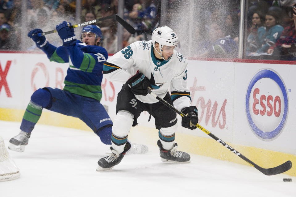 Vancouver Canucks left wing Tanner Pearson (70) fights for control of the puck with San Jose Sharks defenseman Mario Ferraro (38) during the third period of an NHL hockey game Saturday, Jan. 18, 2020, in Vancouver, British Columbia. (Jonathan Hayward/The Canadian Press via AP)