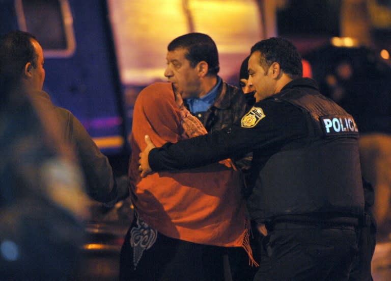 Tunisian police console a family member of one of the victims of a bomb blast on a bus transporting Tunisia's presidential guard in central Tunis on November 24, 2015