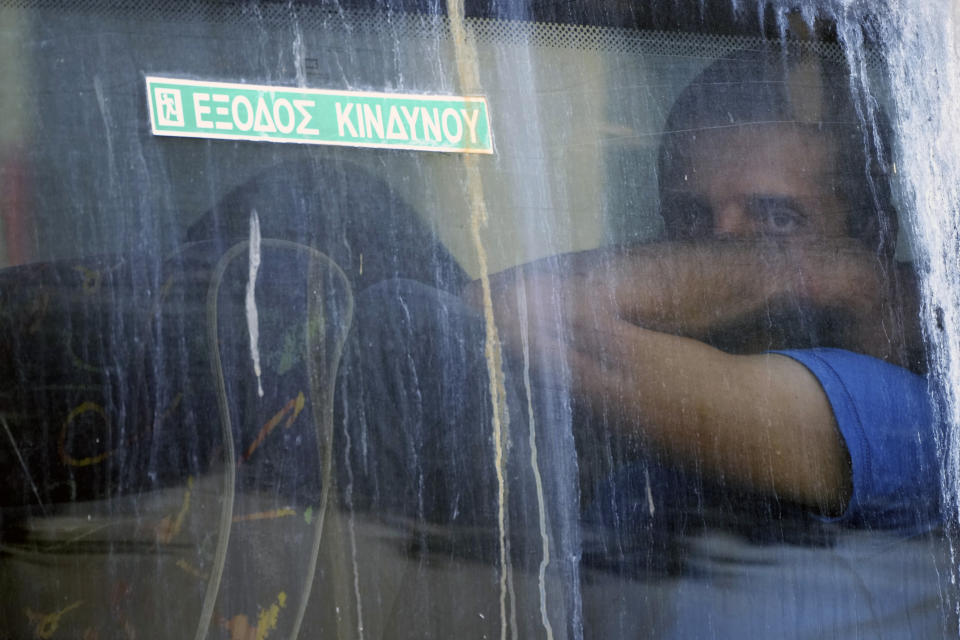 A soccer fan sits inside a police bus upon his departure from the Athens Police Headquarters, Greece, Wednesday, Aug. 9, 2023. Ninety-four fans of Croatia's Dinamo Zagreb are appearing in court this morning for a preliminary hearing over Monday night's fan violence that left a fan of Greece's AEK dead and another eight people injured. The sign on the window reads "Emergency Exit." (AP Photo/Petros Giannakouris)