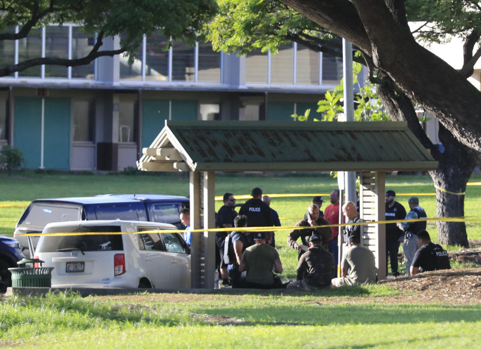 Honolulu police assess the scene around a stolen vehicle stolen on University Avenue, Monday, Jan. 1, 2024, in Honolulu. Authorities in Hawaii say a man shot and wounded a woman, stole a car at gunpoint and was later killed in a shootout with police that left two officers wounded. (Jamm Aquino/Honolulu Star-Advertiser via AP)