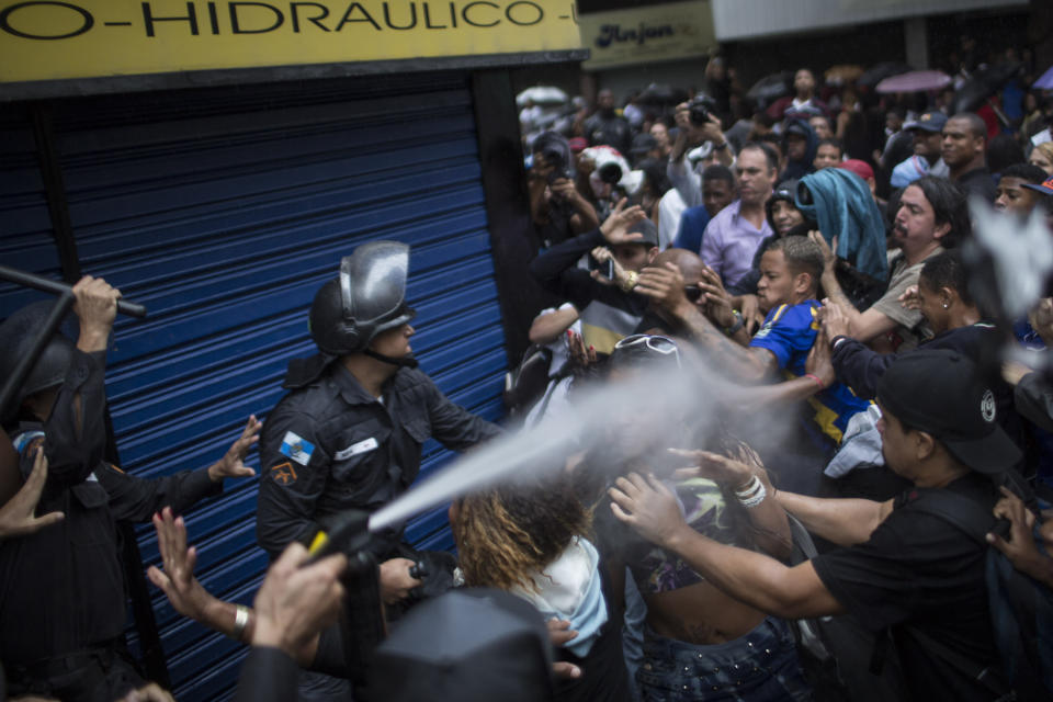 A woman is pepper sprayed as residents of Pavao-Pavaozinho slum clash with riot police during a protest against the death of Douglas Rafael da Silva Pereira after his burial in Rio de Janeiro, Brazil, Thursday, April 24, 2014. The shooting death of Pereira sparked clashes Tuesday night between police and residents of the Pavao-Pavaozinho slum. (AP Photo/Felipe Dana)