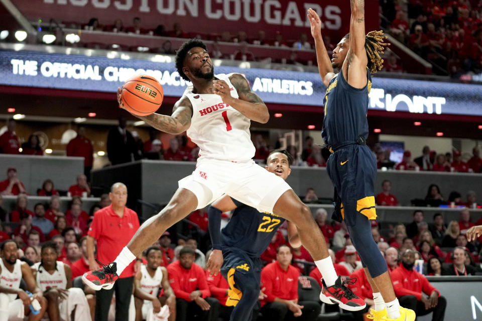 Houston guard Jamal Shead (1) passes as West Virginia guard Noah Farrakhan defends during the second half of an NCAA college basketball game Saturday Jan. 6, 2024, in Houston. (AP Photo/Eric Christian Smith)