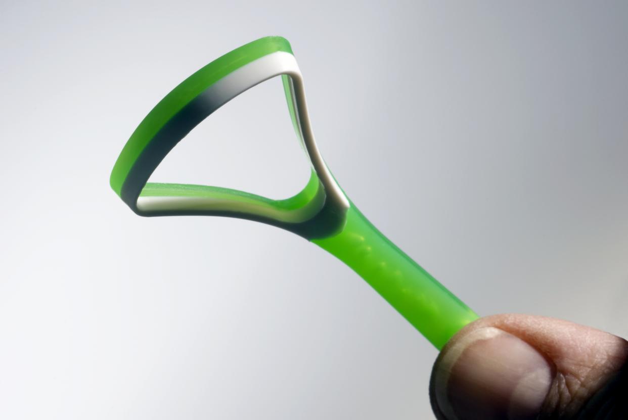 Un raspador de lengua es una pieza de metal o plástico larga, delgada y plana que se dobla en forma de 